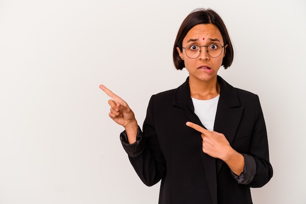 Junge Geschäftsindische Frau lokalisiert auf weißem Hintergrund schockiert mit Zeigefingern auf einen Kopienraum zeigend.