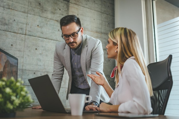 Junge Geschäftskollegen arbeiten am Computer, analysieren Projekte und unterhalten sich im Büro darüber.