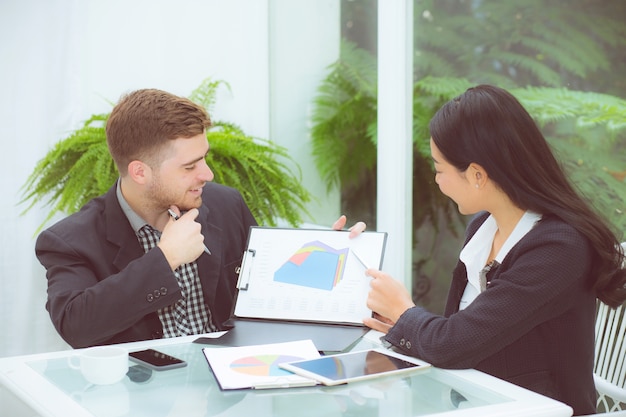 junge Geschäftsleute, die das Treffen und das Sprechen für das Analysieren des Marketings machen, das im Büro arbeitet