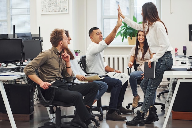 Junge Geschäftsleute feiern Erfolg im modernen Büro.