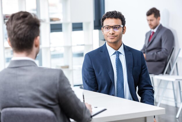 Junge Geschäftsleute in formeller Kleidung, die bei Vorstellungsgesprächen im Büro sitzen und sprechen, Geschäftskonzept