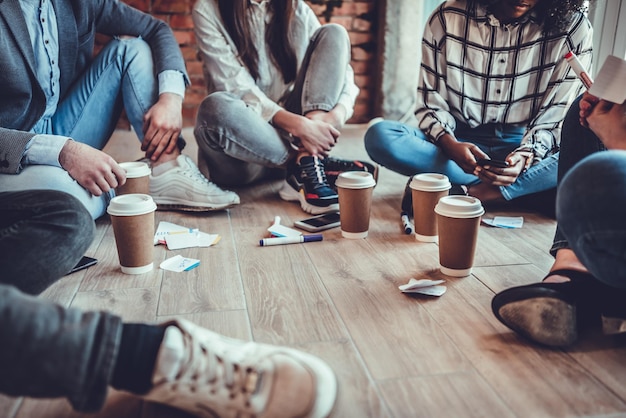 Junge Geschäftsleute in Freizeitkleidung besprechen die Arbeit und trinken Kaffee