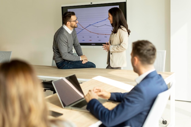 Junge Geschäftsleute präsentieren eine Projektstrategie und zeigen Ideen auf einem interaktiven Whiteboard im Büro