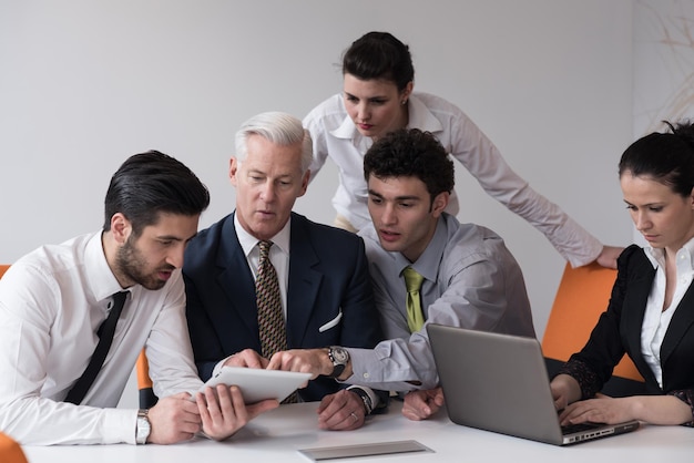 Junge Geschäftsleute treffen sich in einem modernen Startup-Büro mit einem Senior Manager. Teamleiter mit Blick auf Präsentation und Ergebnisse auf Tablet- und Laptop-Computer.