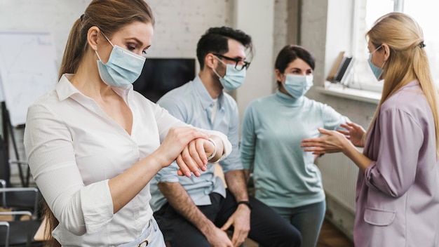 Junge Geschäftsleute während eines Treffens mit medizinischen Masken