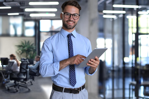 Junge Geschäftsmann benutzt sein Tablet im Büro