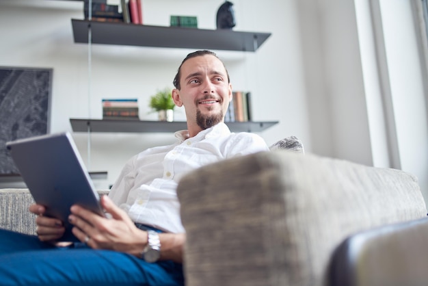 Junge Geschäftsmann mit digitalem Tablet zu Hause