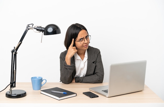 Junge Geschäftsmischrassenfrau, die im Büro arbeitet und eine Idee denkt