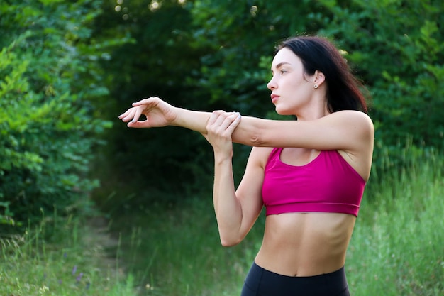 Junge, gesunde, schöne Frau in Sporttop und Leggings, die Sportübungen im Straßensport macht