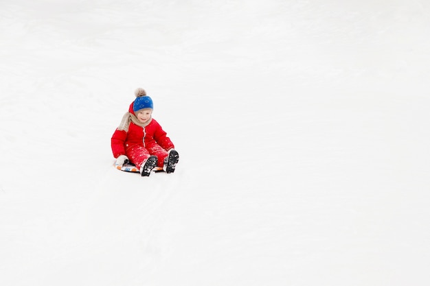 Junge gleitet auf einer Planke im weißen Schnee.