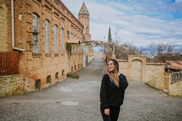 Junge glücklich lächelnde Touristin, die allein reist und mit Attraktionen in einer leeren Straße spaziert