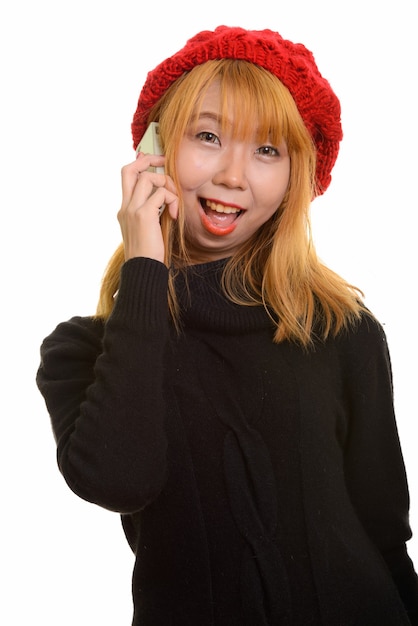 Junge glückliche asiatische Frau, die am Handy lächelt und spricht