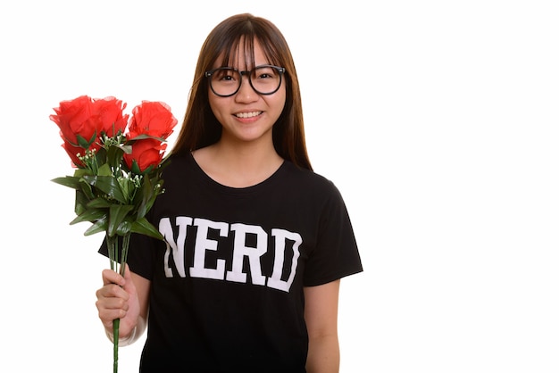 Junge glückliche asiatische Nerd-Teenager-Mädchen lächelnd und hält rote Rosen