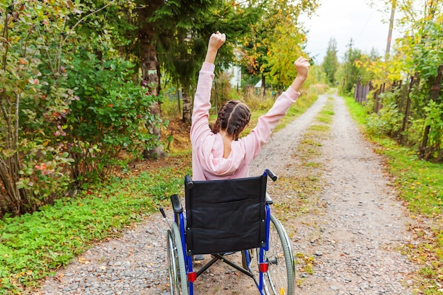 Foto junge, glückliche behinderte frau im rollstuhl auf der straße im krankenhauspark genießt die freiheit