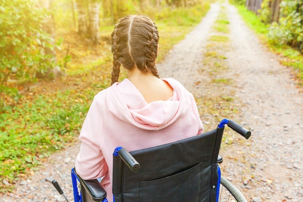 Foto junge, glückliche behinderte frau im rollstuhl auf der straße im krankenhauspark genießt die freiheit