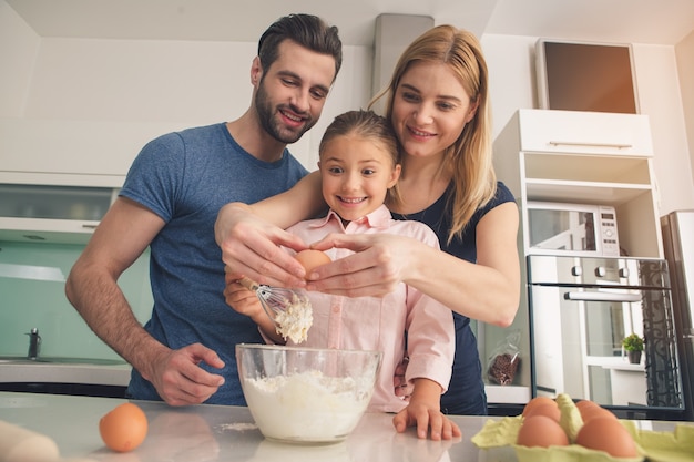 Junge glückliche Familie, die Teig zusammen mischt