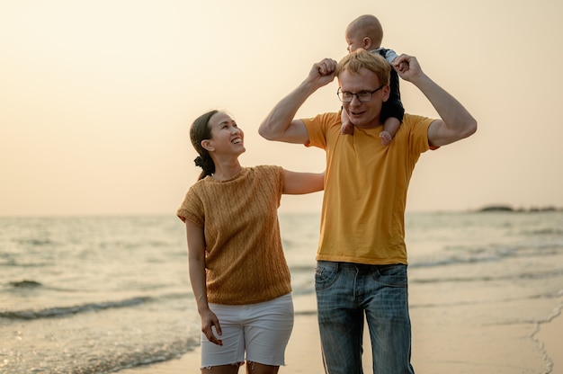 Junge glückliche Familie genießt am Abend Urlaub am Strand Papa Mama und Kind entspannen zusammen spielen