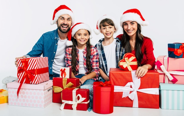 Junge glückliche Familie in Weihnachtsmützen mit Weihnachtsgeschenken