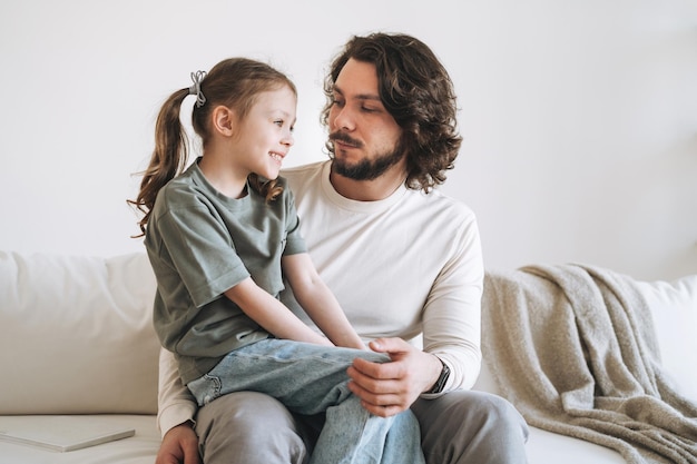 Junge glückliche Familie mit Vater und Tochter auf dem Sofa am gemütlichen Vatertag