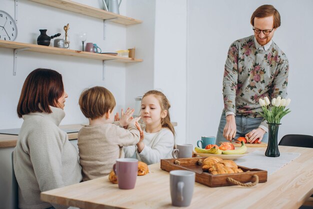 Junge glückliche Familie mit zwei Kindern, die zusammen frühstücken.