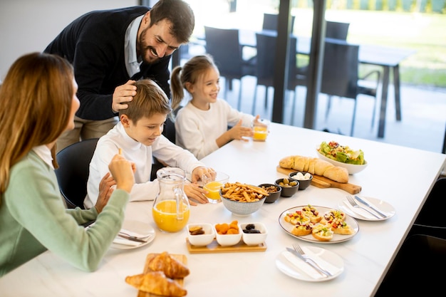 Junge glückliche Familie spricht beim Frühstück am Esstisch in der Wohnung