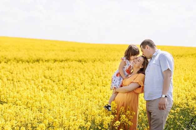 Junge glückliche Familie unter dem gelben blühenden Feld