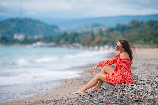 Junge glückliche Frau am Strand mit Blick auf die Berge