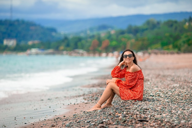 Junge glückliche Frau am Strand mit Blick auf die Berge