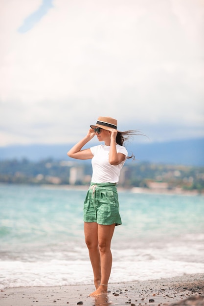 Junge glückliche Frau am Strand mit Blick auf die Berge