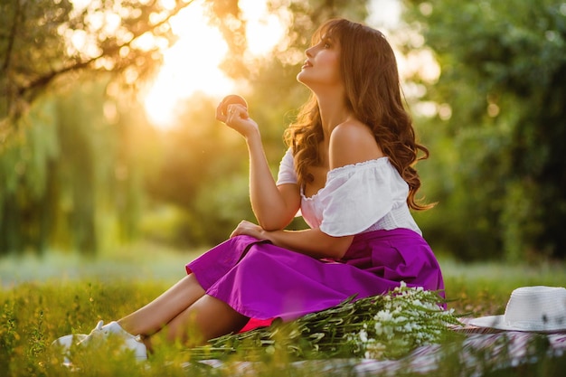 Junge glückliche Frau auf Picknick im Park Foto gegen die Sonne Weiches Sonnenlicht bei Sonnenuntergang