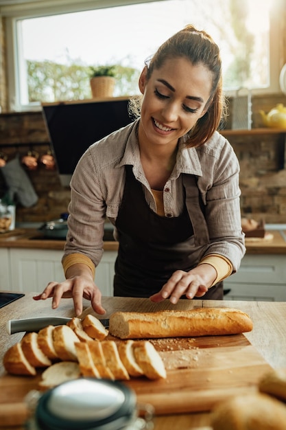 Junge glückliche Frau bereitet eine Mahlzeit zu und verwendet Baguettescheiben in der Küche