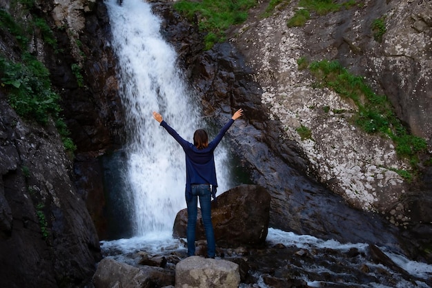 Junge glückliche Frau, die den Sommerwasserfall genießt