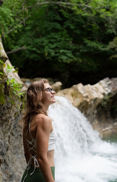 Junge glückliche Frau, die den Wasserfall genießt