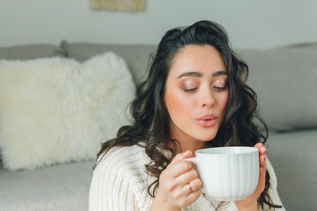 Junge glückliche Frau, die eine Tasse Tee trinkt