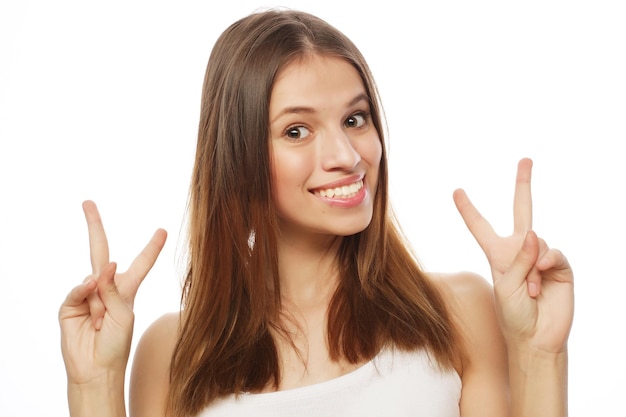 Junge glückliche Frau, die mit dem Finger nach oben auf das Copyspace zeigt, das auf einem weißen Hintergrund isoliert ist