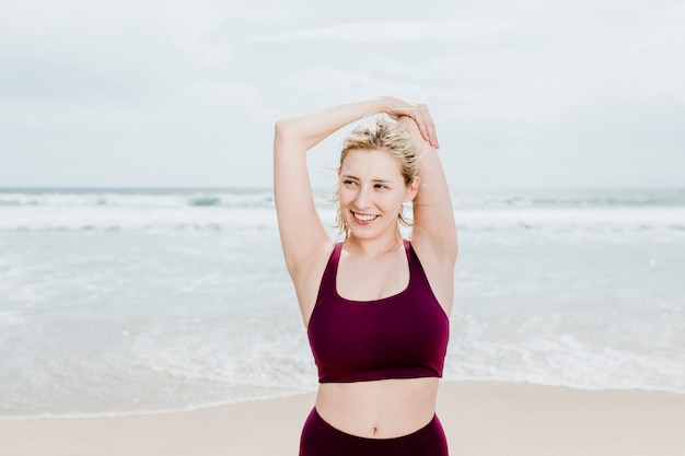 Junge glückliche Frau, die sich am Strand ausdehnt