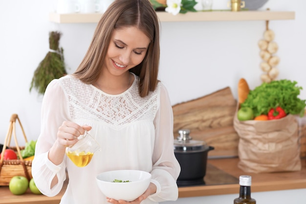 Junge glückliche Frau kocht oder isst frischen Salat in der Küche. Lebensmittel- und Gesundheitskonzept.