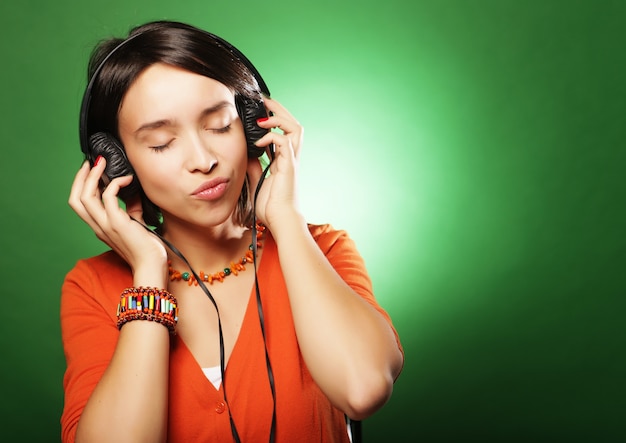 Junge glückliche Frau mit Kopfhörern, die Musik hören