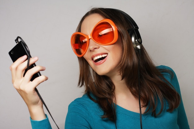 Junge glückliche Frau mit Kopfhörern, die Musik über weißem Hintergrund hören