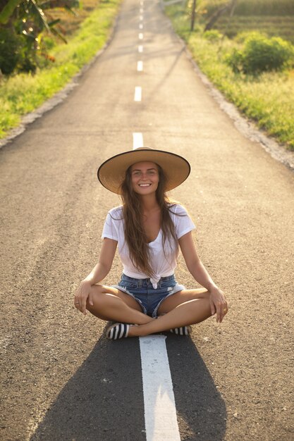 Junge glückliche Frau sitzt in der Mitte der Asphaltstraße
