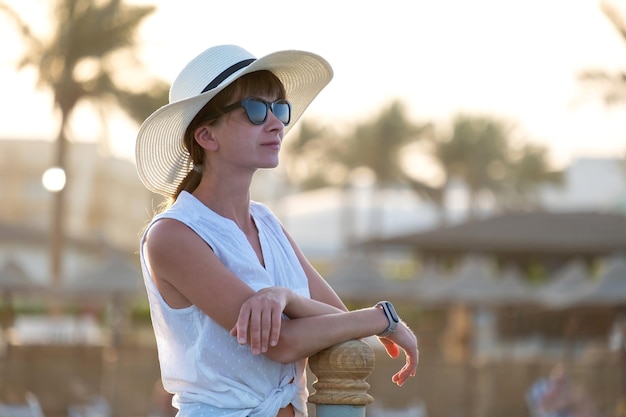 Junge glückliche Frau Tourist im Freien entspannen an warmen sonnigen Abend am Meer. Sommerferien und Reisekonzept.