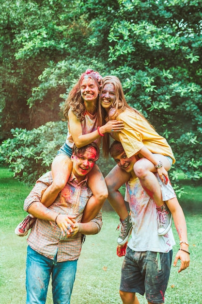 Junge glückliche freunde am indischen traditionellen feiertag holi fest. Frauen auf Männerschultern. huckepack