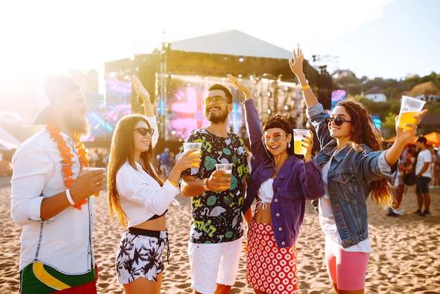 Junge glückliche Freunde trinken Bier und haben Spaß beim Musikfestival zusammen Freundschaft