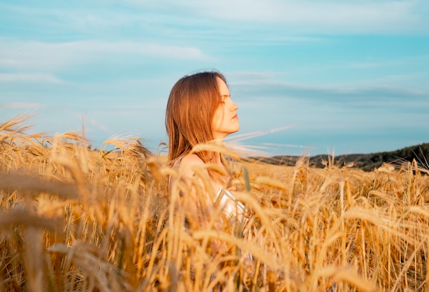 Junge glückliche friedliche Frau im goldenen Weizenfeld im Sommermeditations- und Friedenskonzept