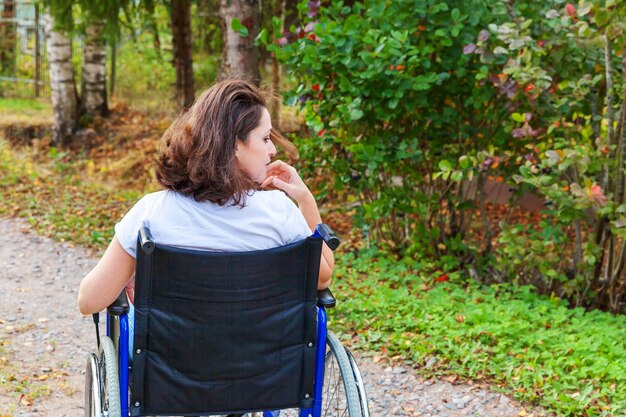 Junge glückliche Handicapfrau im Rollstuhl auf Straße im Krankenhauspark, der Freiheit genießt