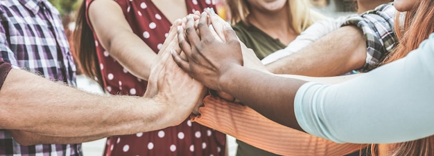 Junge glückliche Leute, die Hände im Freien stapeln. Verschiedene Kulturstudenten feiern zusammen