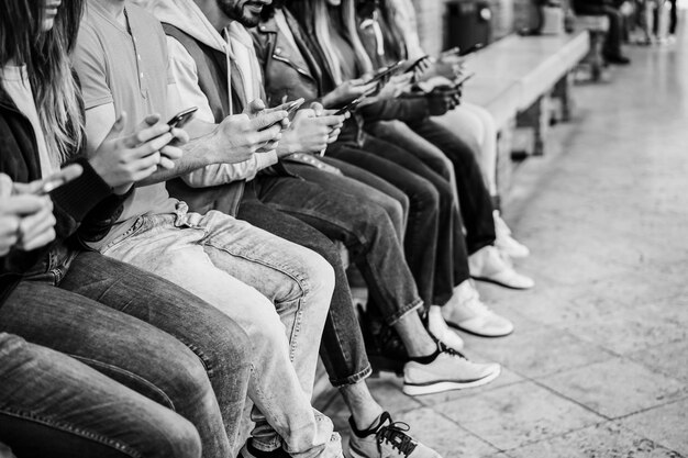 Junge glückliche Menschen, die im Freien Handys benutzen