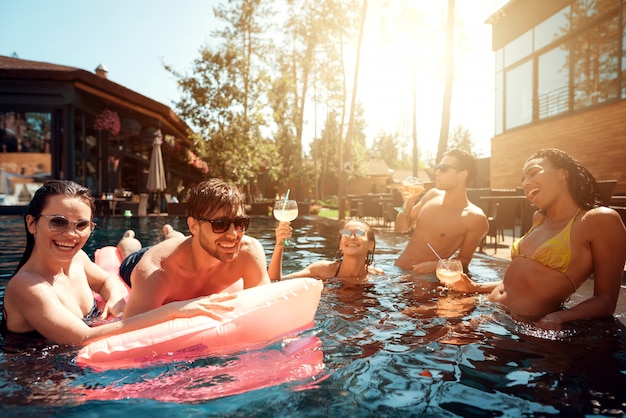 Junge glückliche Menschen, die im Pool schwimmen