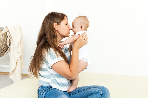 Junge glückliche Mutter, die mit kleinem Baby spielt