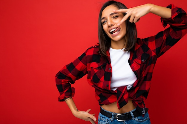 Junge glückliche positive sexy attraktive brünette Frau mit aufrichtigen Gefühlen, die weißes T-Shirt und Hipster rotes Karohemd tragen